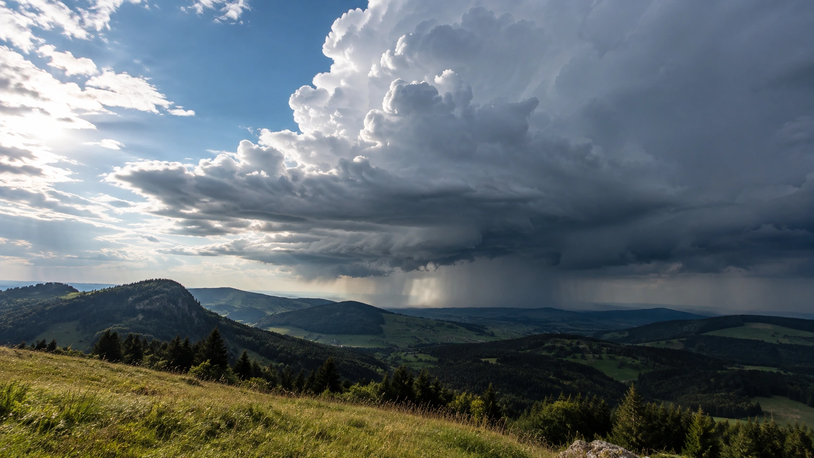 Ausgeprägte Gewitterwolke mit Niederschlagskern über einer offenen Hügellandschaft.