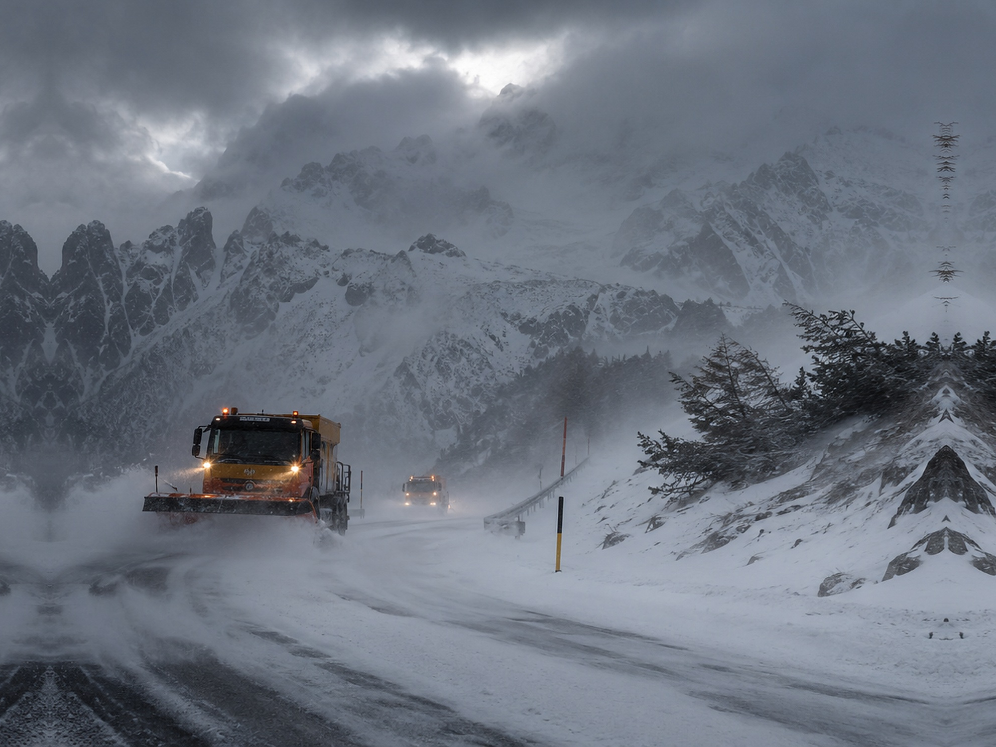 Schneesturm in den Alpen mit starkem Wind, schlechter Sicht und einem Räumfahrzeug auf verschneiter Strasse